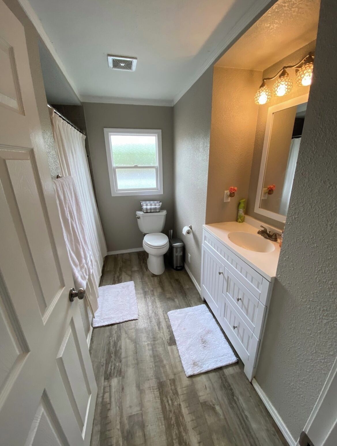 A bathroom with a toilet, sink, vanity, and a window.