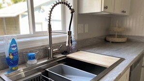 A modern kitchen with a stainless steel sink, a dish soap bottle, and a dish brush. - Home Sweet Home (Sutherlin)