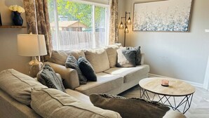 A living room with a sofa, a coffee table, a lamp, and a painting on the wall. - Home Sweet Home (Sutherlin)
