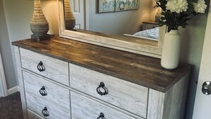 A wooden dresser with six drawers, a mirror, a lamp, and a vase with flowers. - Home Sweet Home (Sutherlin)