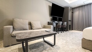 A modern living room with a sofa, a coffee table, a flat-screen TV, and a dining area with chairs. - Chungju Browndot Cityhall (Chungju)
