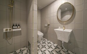 Un baño con ducha, inodoro, lavabo y espejo.