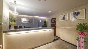 A hotel reception area with a modern design, featuring a reception desk, a wall-mounted sign, and framed artwork on the wall. - Chungju Browndot Cityhall (Chungju)