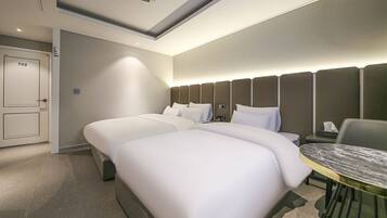 A hotel room with a double bed, a desk with a chair, and a door marked with the number 702.