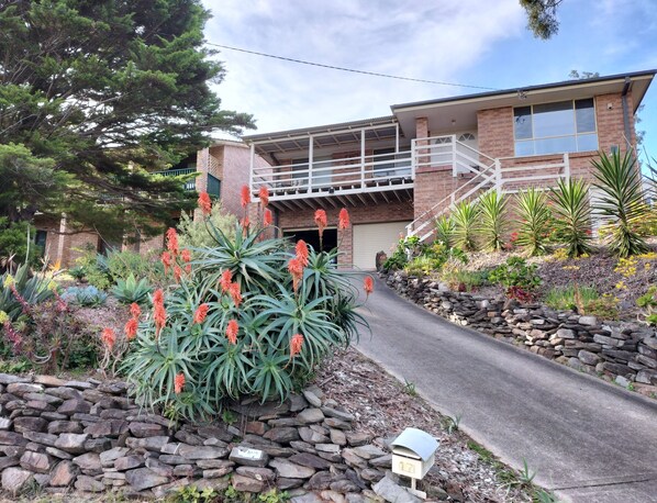 A two-story house with a stone pathway leading to the entrance, surrounded by various plants and a mailbox. - Mountain View Beach House Near Batemans Bay (Catalina)