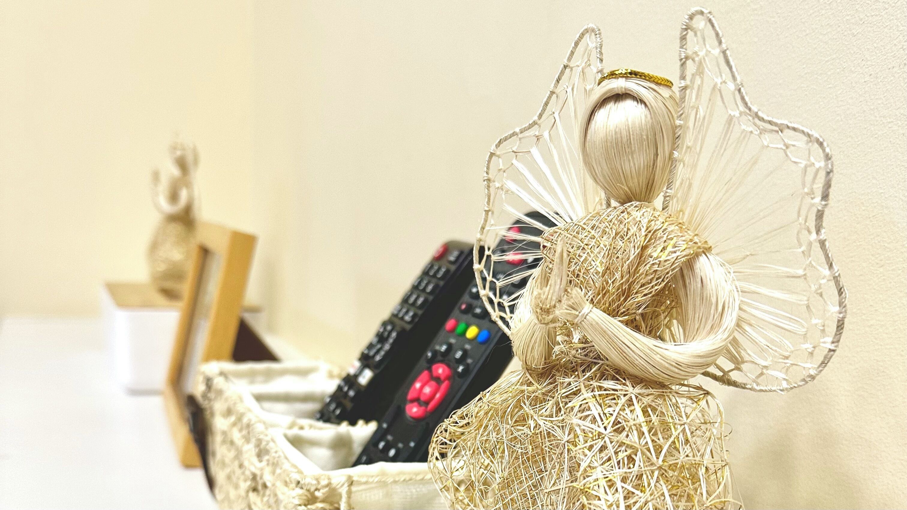A decorative angel figurine with a basket containing remote controls.