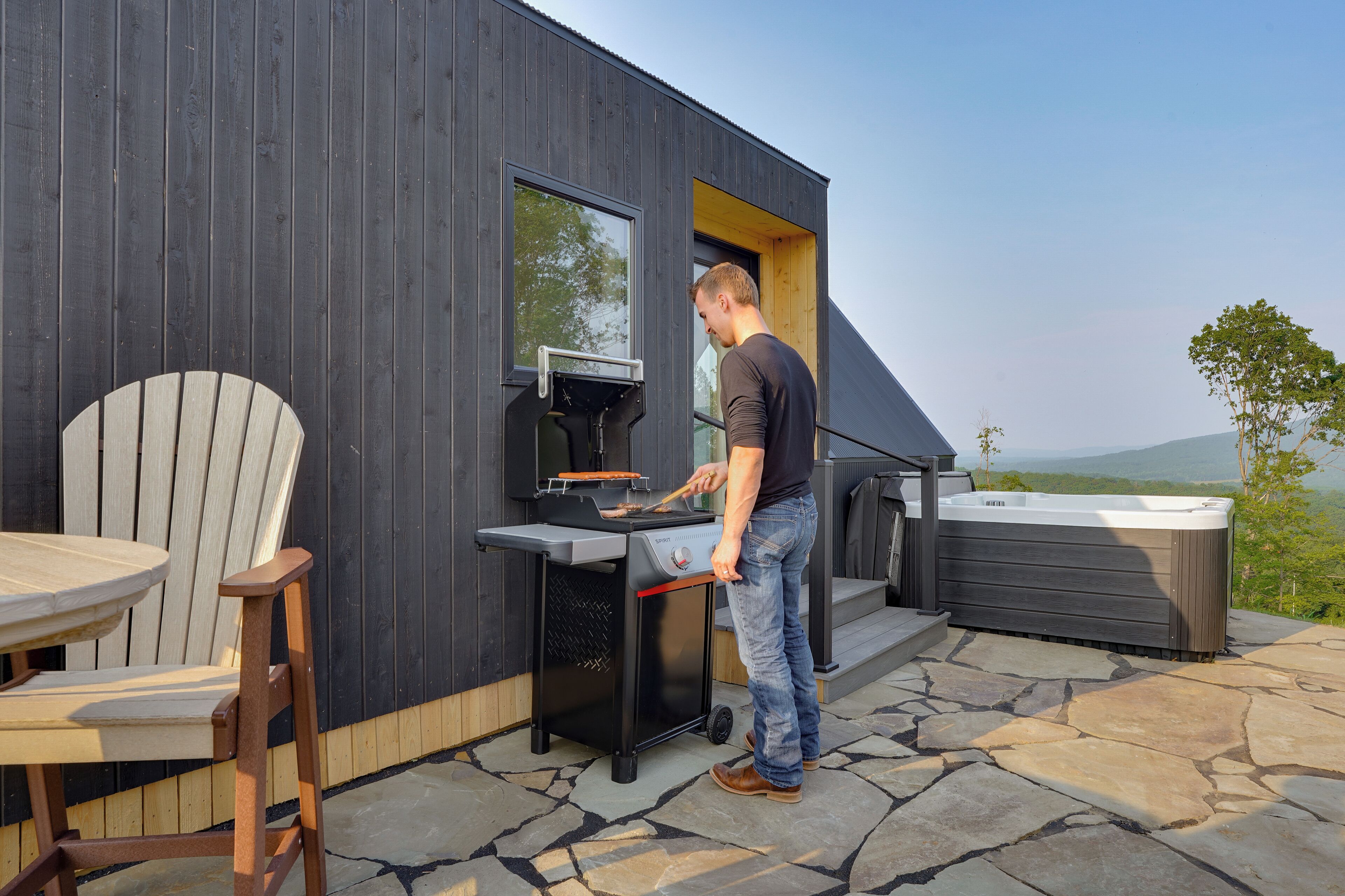 Een moderne buitenkeuken met een barbecue, een jacuzzi en een terras van natuursteen.