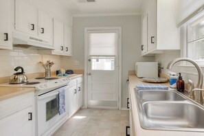 Une cuisine moderne avec des meubles blancs, une cuisinière, un évier et une fenêtre.