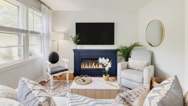 A living room with a fireplace, a television mounted above it, and a comfortable seating area with a sofa and armchairs. - The Powder Cottage by Avantstay Heart of Old Mt. Pleasant Near Sullivans (Mount Pleasant)