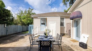 A patio with a table set for four, a small deck, and a house with a blue door and white siding. - The Powder Cottage by Avantstay Heart of Old Mt. Pleasant Near Sullivans (Mount Pleasant)