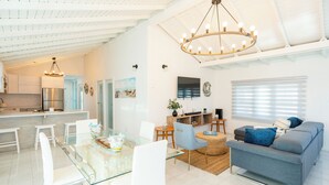 A modern living space with a dining area, sofa, and kitchen.