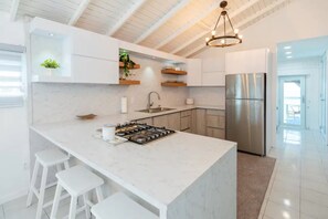 A modern kitchen with a central island, stainless steel appliances, and a high ceiling with exposed beams.