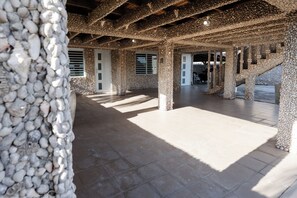 A spacious interior with stone pillars, a tiled floor, and a view of the outside.