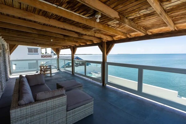 A covered outdoor seating area with a view of the ocean.