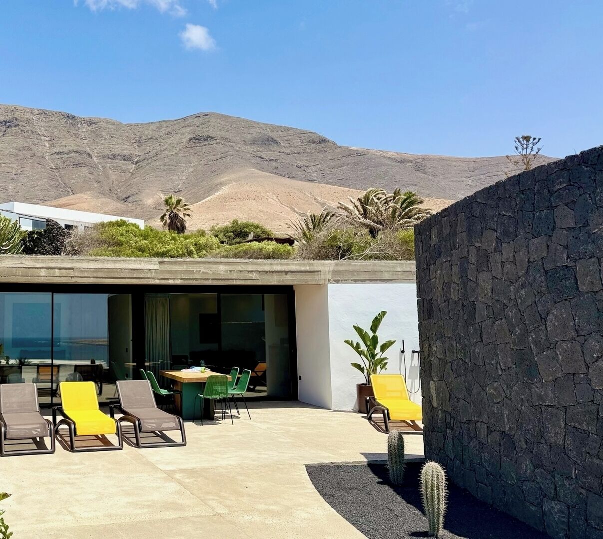 Un espacio lounge moderno al aire libre con piscina, asientos y vistas a un paisaje montañoso.