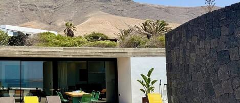 Un espacio lounge moderno al aire libre con piscina, asientos y vistas a un paisaje montañoso.