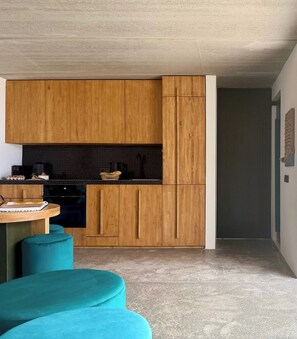 Cozinha moderna com arm ários de madeira, painel de fundo preto e bancada azul.