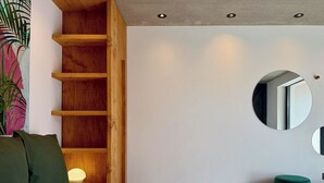 Een moderne slaapkamer met een groot bed, een houten wandplank, een bedlamp en een spiegel aan de muur.
