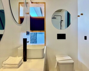 Une salle de bain moderne avec un lavabo blanc, un miroir et des toilettes.