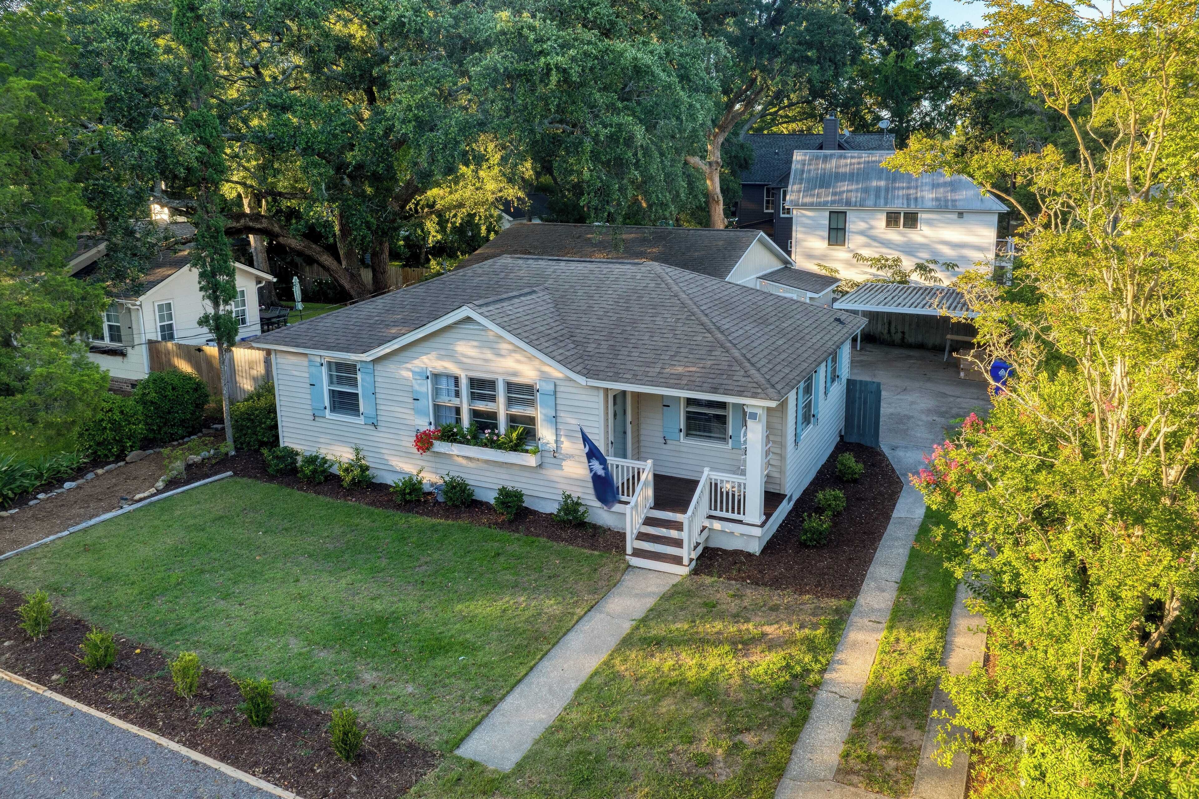 A single-story house with a front porch, a small front yard, and a flag.