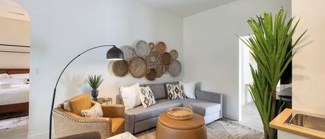 A modern living room with a sofa, armchair, ottoman, and a wall decorated with circular woven items.
