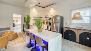 A modern kitchen with a marble island, stainless steel appliances, and a hanging light fixture. - The Cannon Cottage by Avantstay Old Mt. Pleasant Gem Near Sullivans Island (Mount Pleasant)