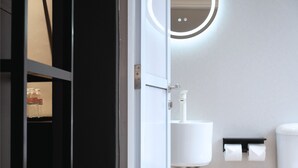 A modern bathroom with a white sink, a toilet, and a shelf with bottled water. - Asphodel Inn - Newly Renovated (Singapore)