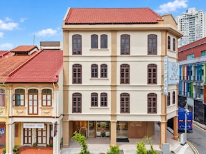 Um edifício de vários andares com telhado de telhas vermelhas, janelas amplas e uma fachada com a inscrição 'George'.