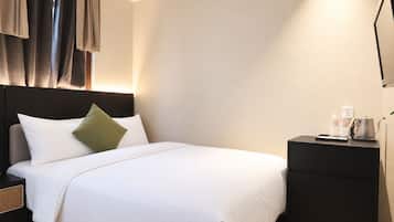 Quarto de hotel com cama, mesas de cabeceira e criadeira.