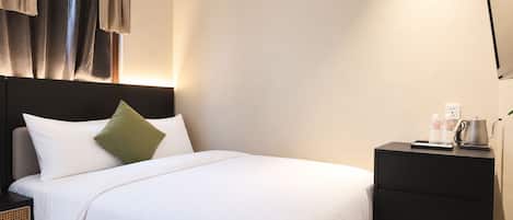 Una habitación de hotel con una cama, mesitas de noche y una mesilla.