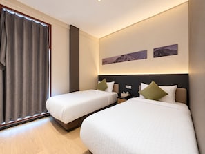 A hotel room with two beds, a large window with curtains, a nightstand, and a wall-mounted artwork. - Asphodel Inn - Newly Renovated (Singapore)