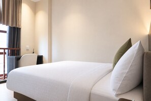 A hotel room with a large bed, a desk, and a chair. - Asphodel Inn - Newly Renovated (Singapore)