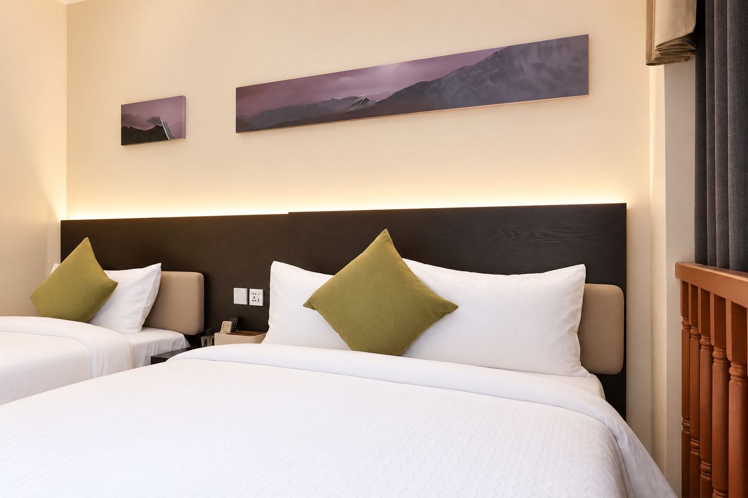 A hotel room with two beds, a dark headboard, and artwork on the wall.
