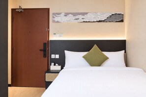 A hotel room with a bed, a nightstand, a wall-mounted artwork, and a door. - Asphodel Inn - Newly Renovated (Singapore)