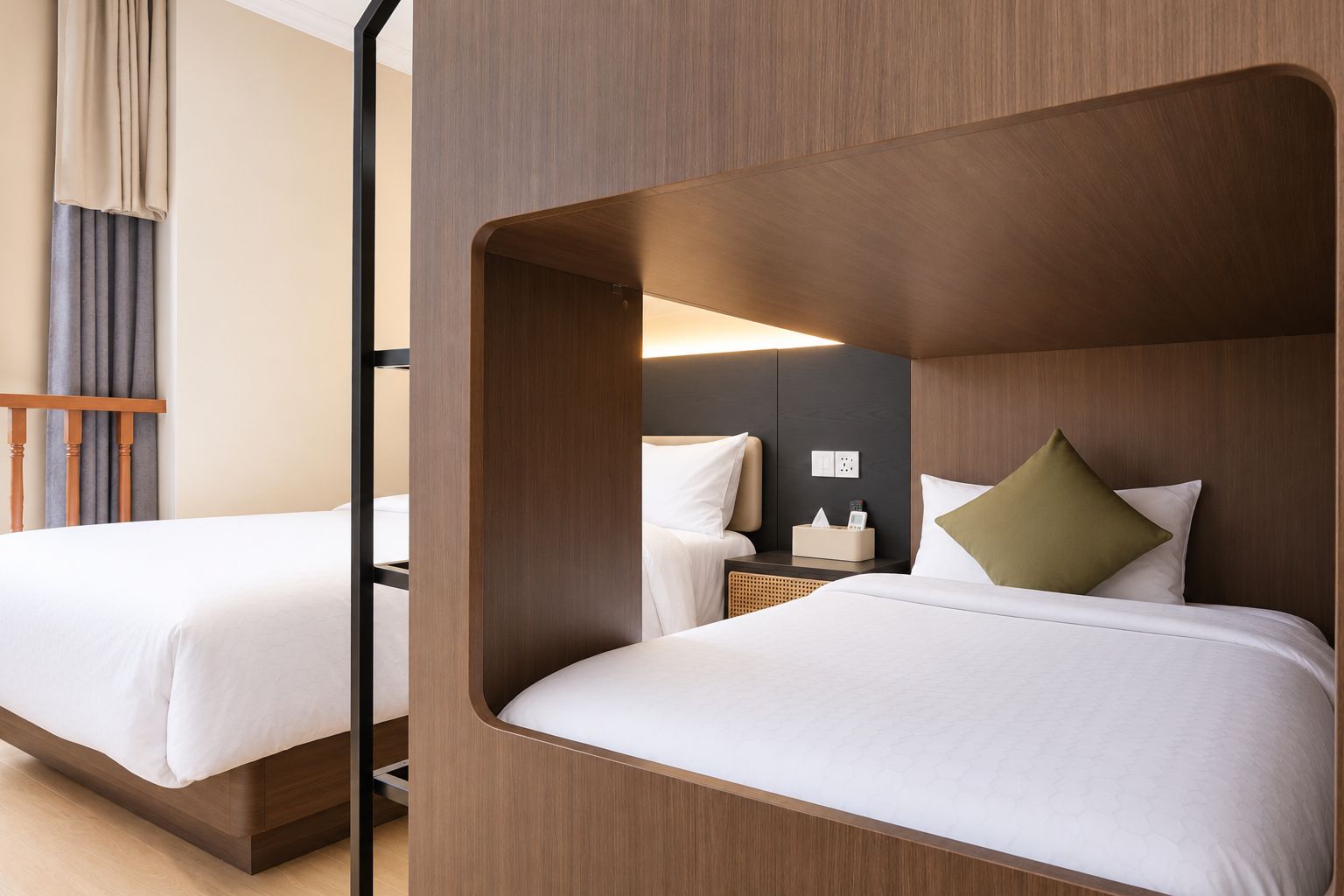A hotel room with two beds, a wooden headboard, a bedside table with a lamp, and a wall socket.