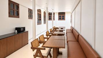 A long dining area with wooden tables and chairs, a counter with a microwave, and a bench along the wall.