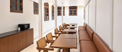 A long dining area with wooden tables and chairs, a counter with a microwave, and a bench along the wall.