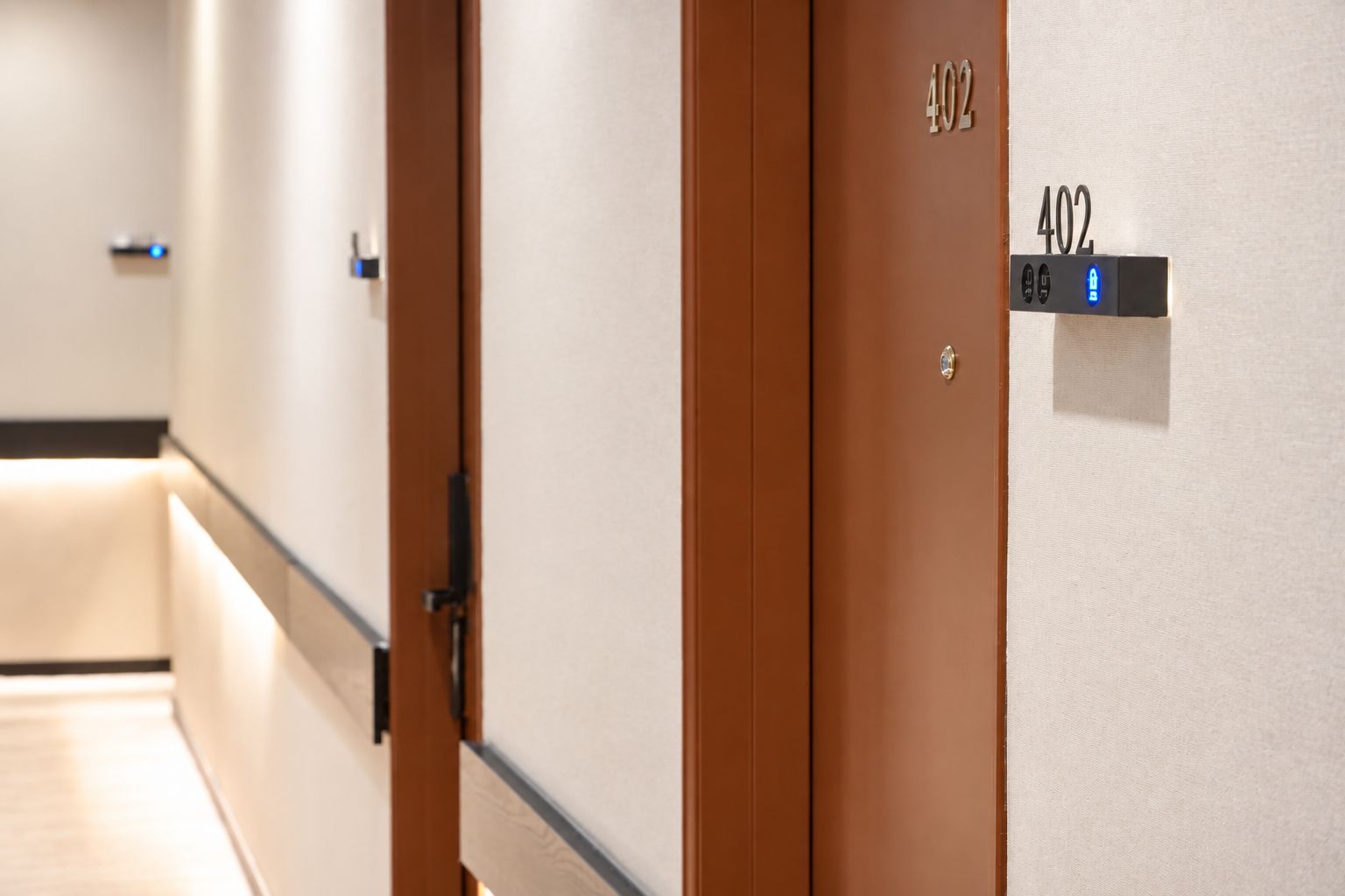 A hotel corridor with doors numbered 402, a light switch, and a door handle.