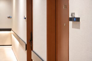 Un couloir d’hôtel avec des portes numérotées 402, un interrupteur et une poignée de porte.