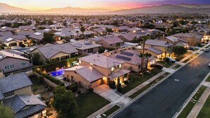 A residential area with houses, streets, and a sunset in the background. - Casa Campo 5BR Desert Oasis w/ Pool, Firepit, & Outdoor Lounge (Indio)