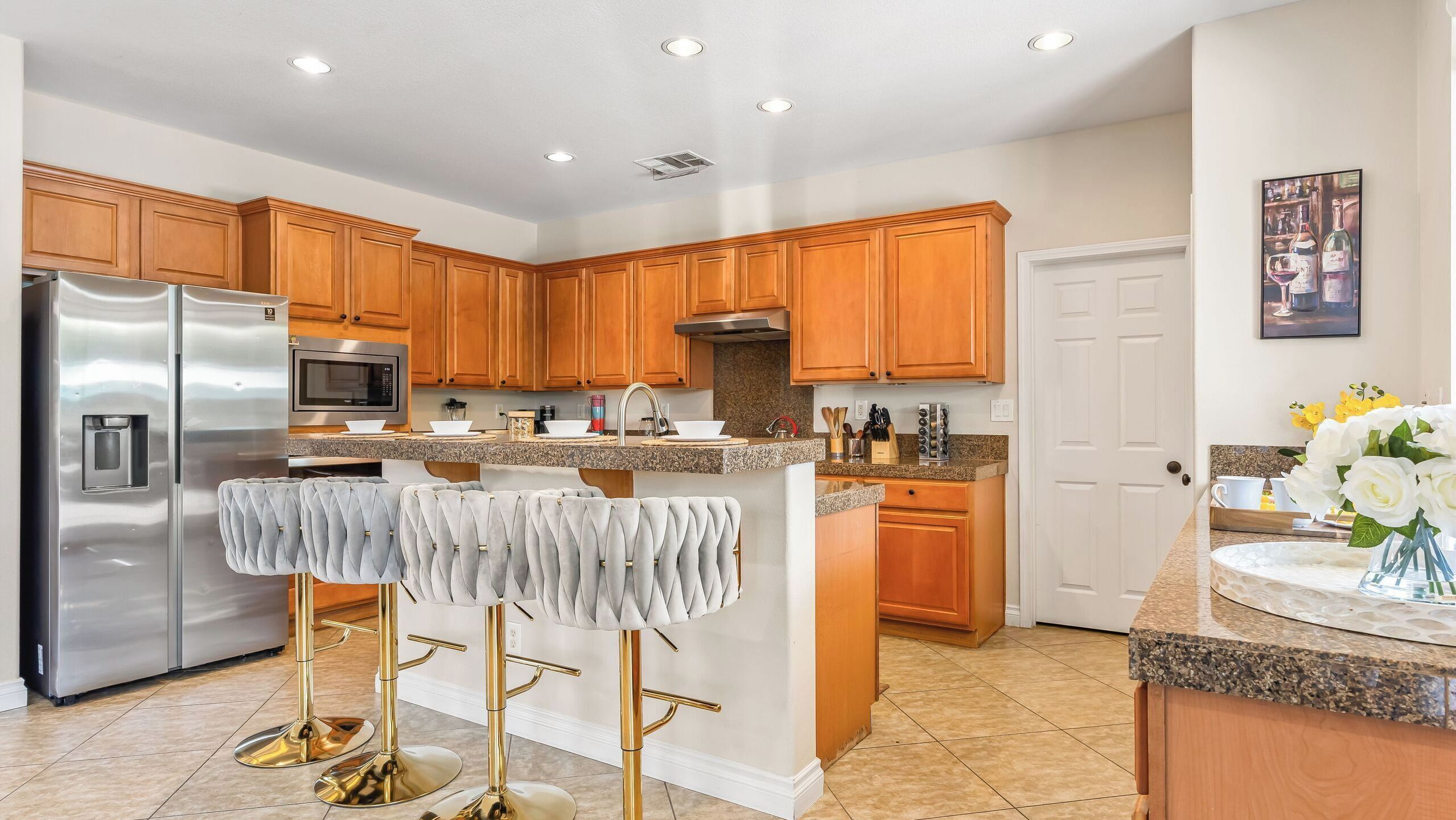 A modern kitchen with wooden cabinets, stainless steel appliances, and a central island with bar stools.