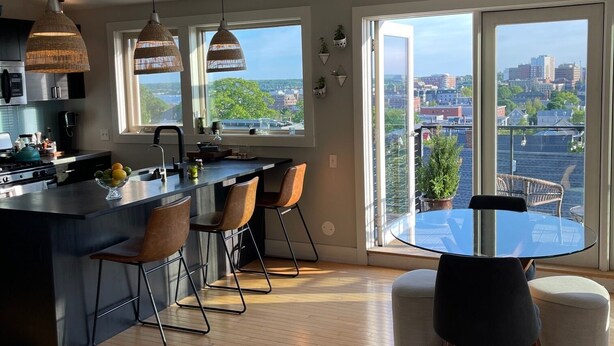 Una cocina moderna con una isla central, taburetes de bar e iluminación colgante.