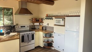 Una cocina compacta con vigas de madera, estufa, microondas y refrigerador.