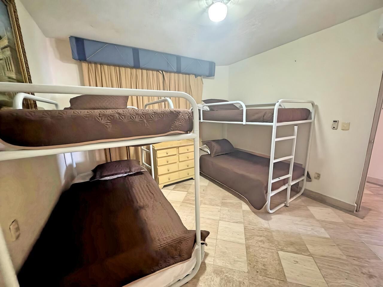 Una habitación con literas, un aparador de madera y un ventilador de techo.