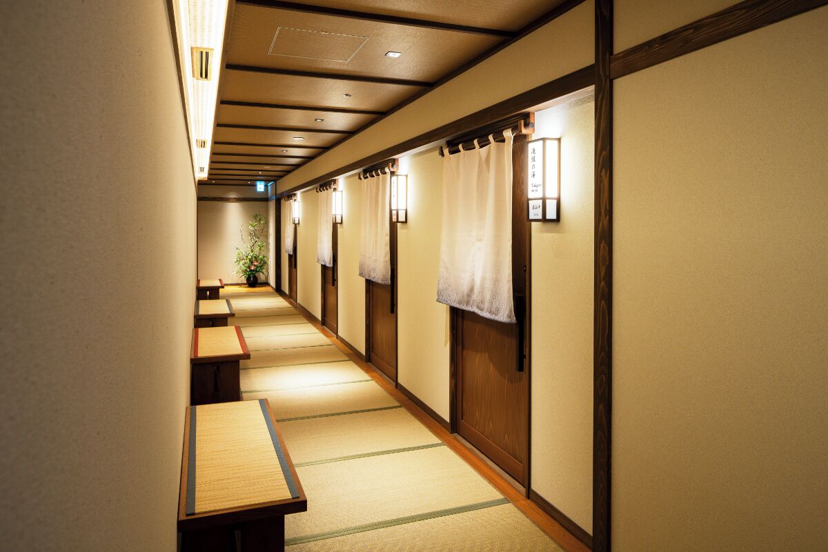 Un pasillo con esteras de tatami, puertas de madera y faroles japoneses tradicionales.