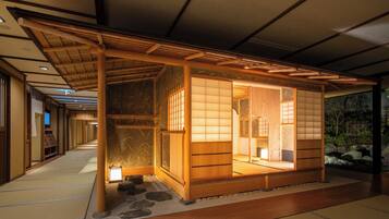 A traditional Japanese room with tatami flooring, sliding doors, and a small stone garden.