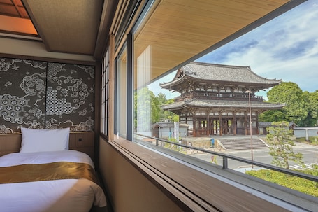 A hotel room with a large window overlooking a traditional Japanese building.