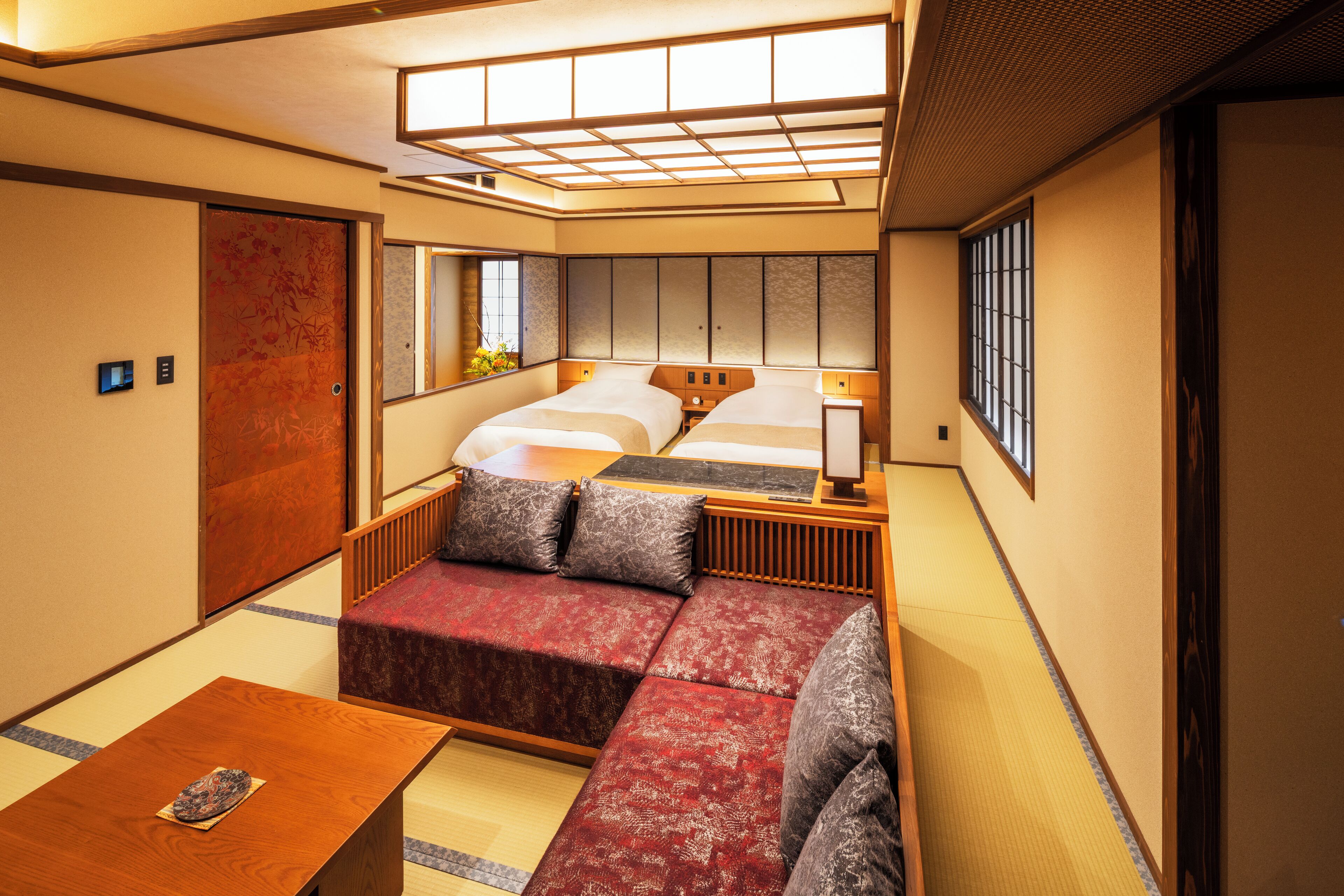 Ein traditioneller japanischer Raum mit Tatami-Böden, einem niedrigen Holzbett mit Futon und einer verschiebbaren Shoji-Schiebetür.