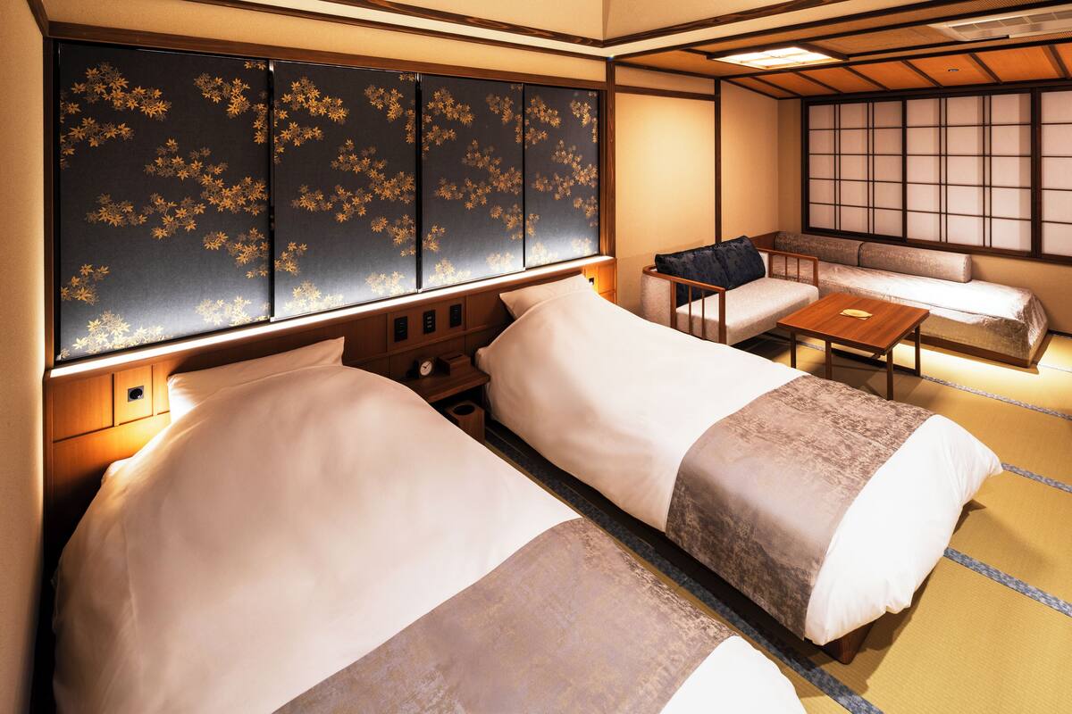 Una habitación tradicional japonesa con dos camas, una mesita y un sofá.