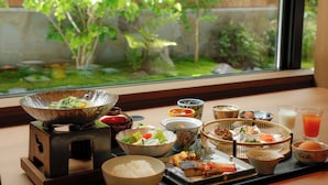 A traditional Japanese meal setup with various dishes and a view of a garden through a window. - Kyoto Omuro Kadensho（Kyoritsu Resorts） (Kyoto)
